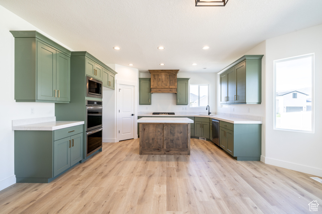 Kitchen with appliances with stainless steel finishes, green cabinetry, light wood-style flooring, a center island, and recessed lighting