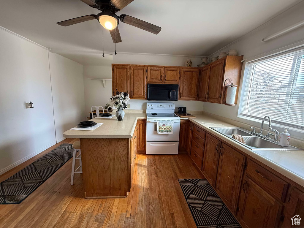 Kitchen featuring black microwave, electric range, visible vents, a kitchen breakfast bar, and light countertops