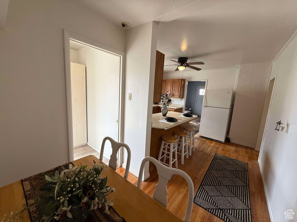 Dining area featuring light wood-type flooring, ceiling fan, and baseboards