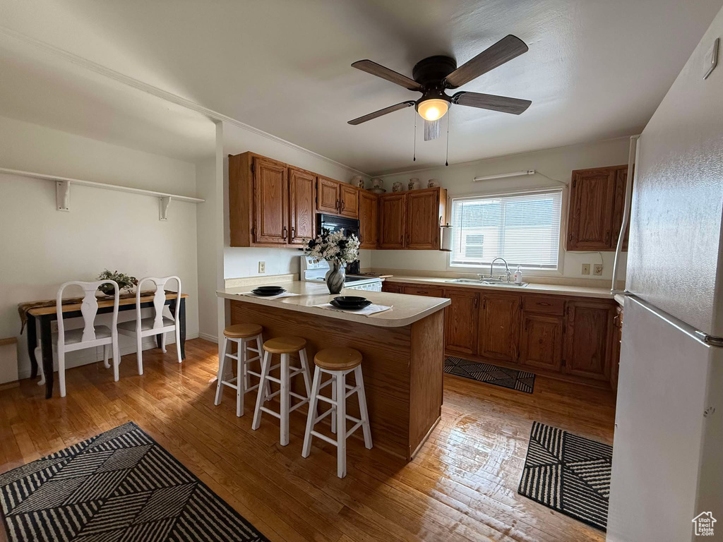 Kitchen featuring brown cabinets, white appliances, and light countertops