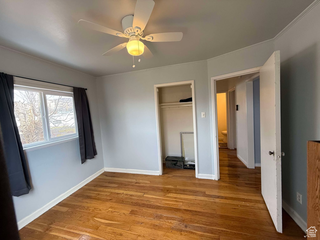 Unfurnished bedroom with baseboards, a ceiling fan, light wood-style flooring, crown molding, and a closet