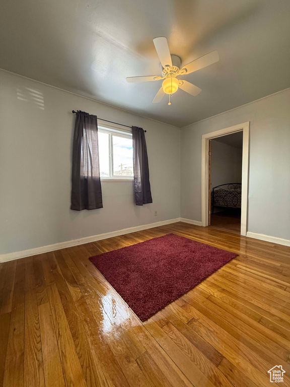 Spare room with wood finished floors, a ceiling fan, and baseboards