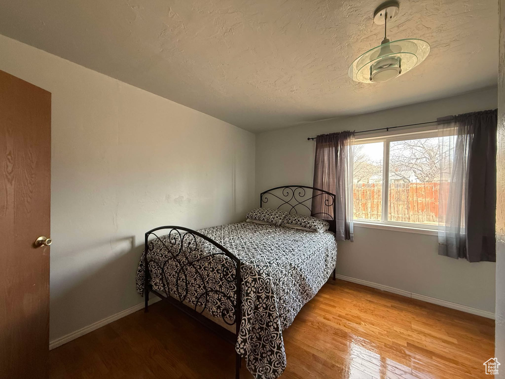 Bedroom with a textured ceiling, baseboards, and wood finished floors