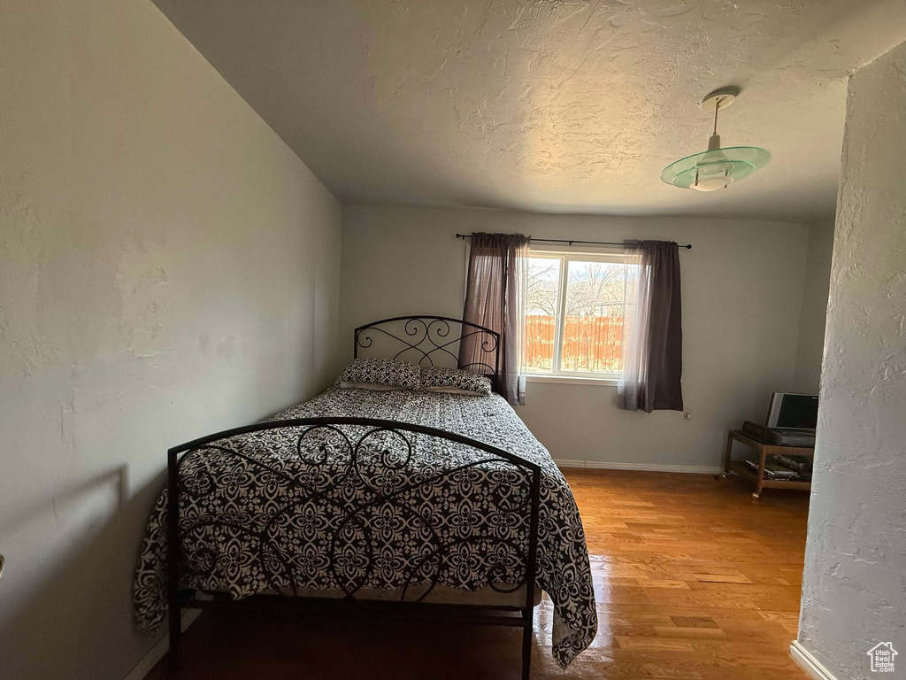 Bedroom featuring a textured ceiling, baseboards, wood finished floors, and a textured wall