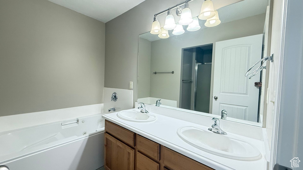 Bathroom featuring a whirlpool tub, double vanity, a sink, and a shower with shower door