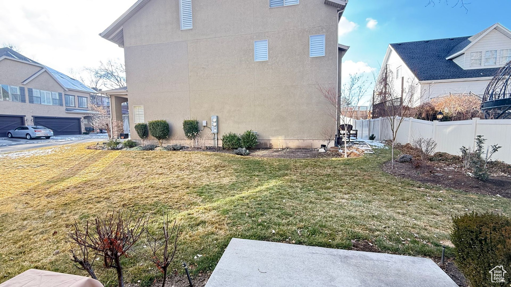 View of side of home featuring a yard, fence, and stucco siding