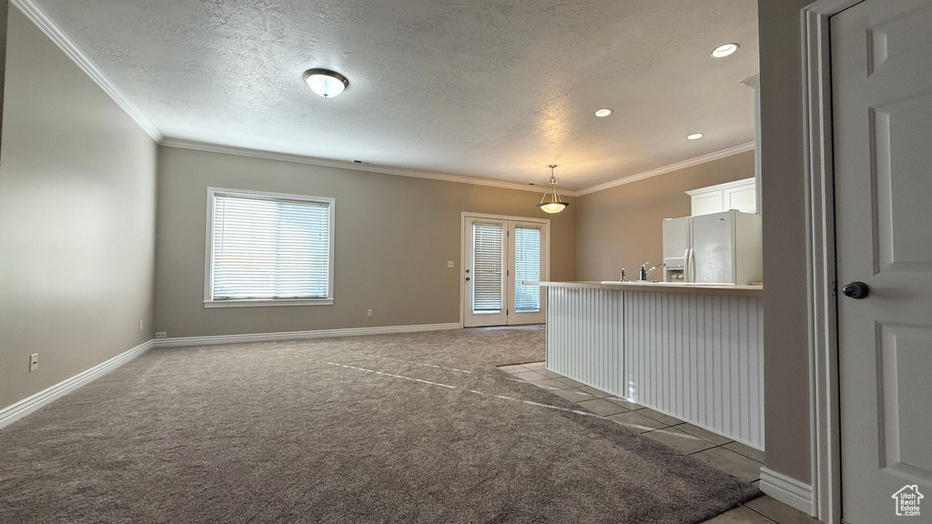 Carpeted empty room featuring a sink, a textured ceiling, baseboards, and crown molding