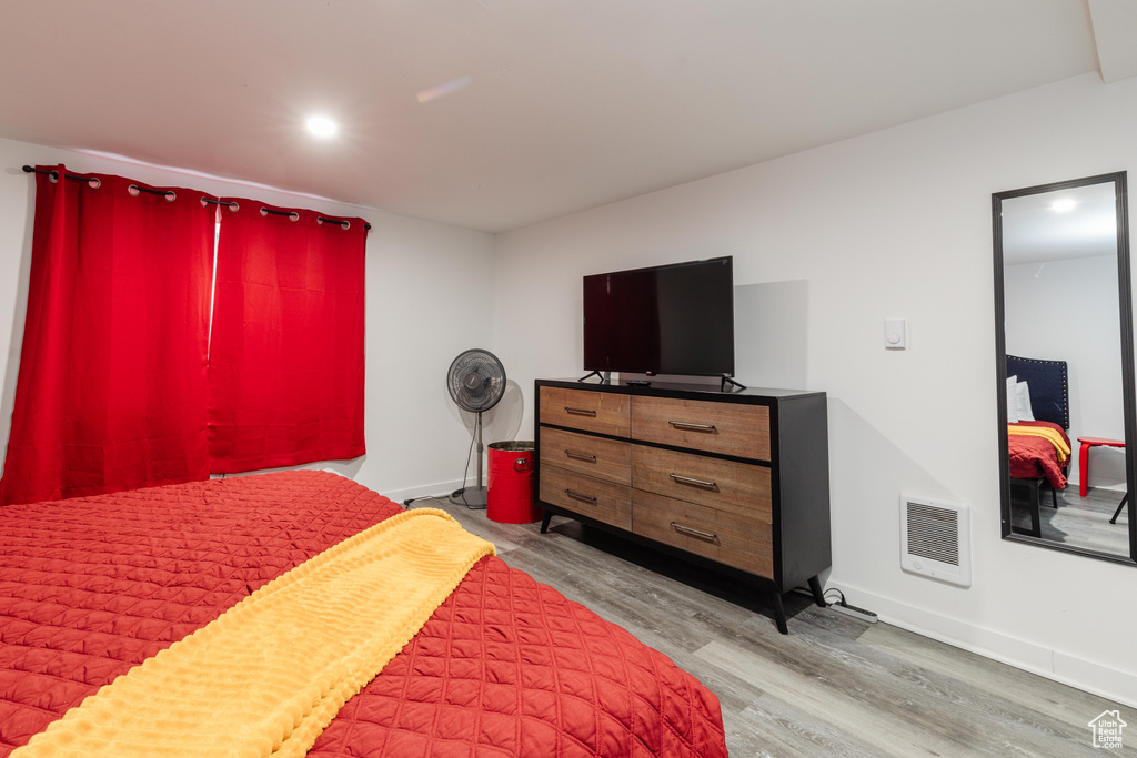 Bedroom with light wood finished floors, visible vents, and baseboards