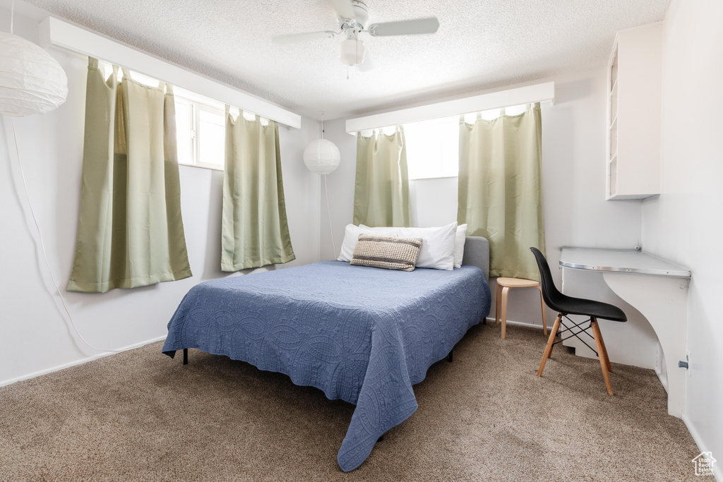 Bedroom with carpet, a ceiling fan, and a textured ceiling