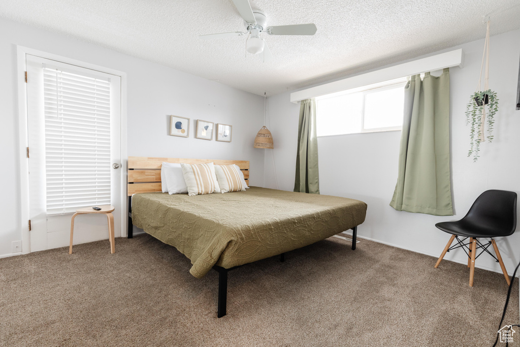 Carpeted bedroom featuring a ceiling fan and a textured ceiling