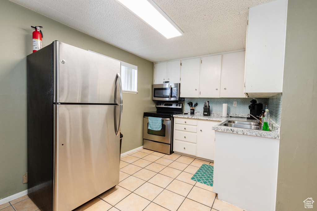 Kitchen with a sink, stainless steel appliances, light countertops, and white cabinets