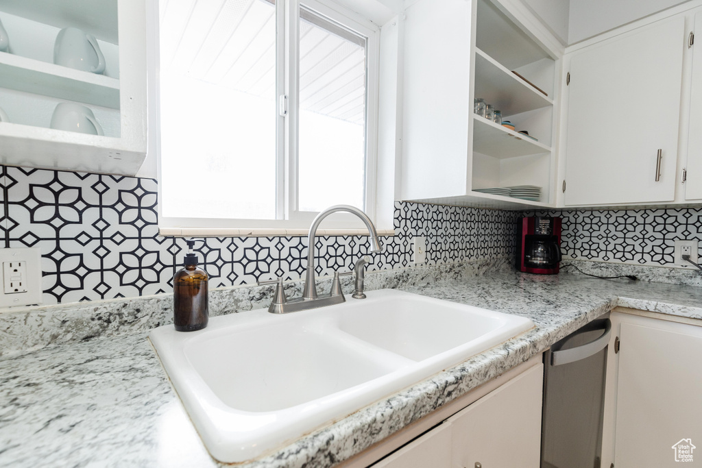 Kitchen featuring white cabinetry, decorative backsplash, and a sink