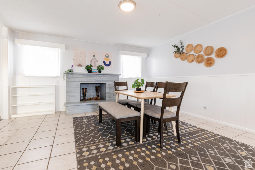 Dining area featuring wainscoting, light tile patterned flooring, and a fireplace