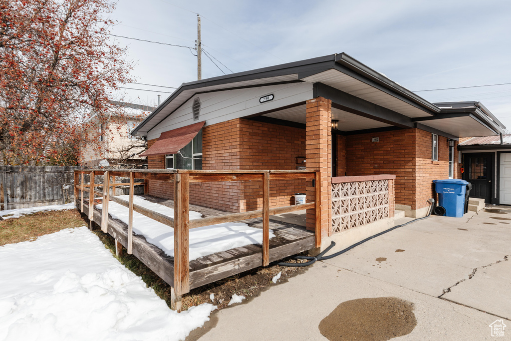 View of snowy exterior featuring fence and brick siding