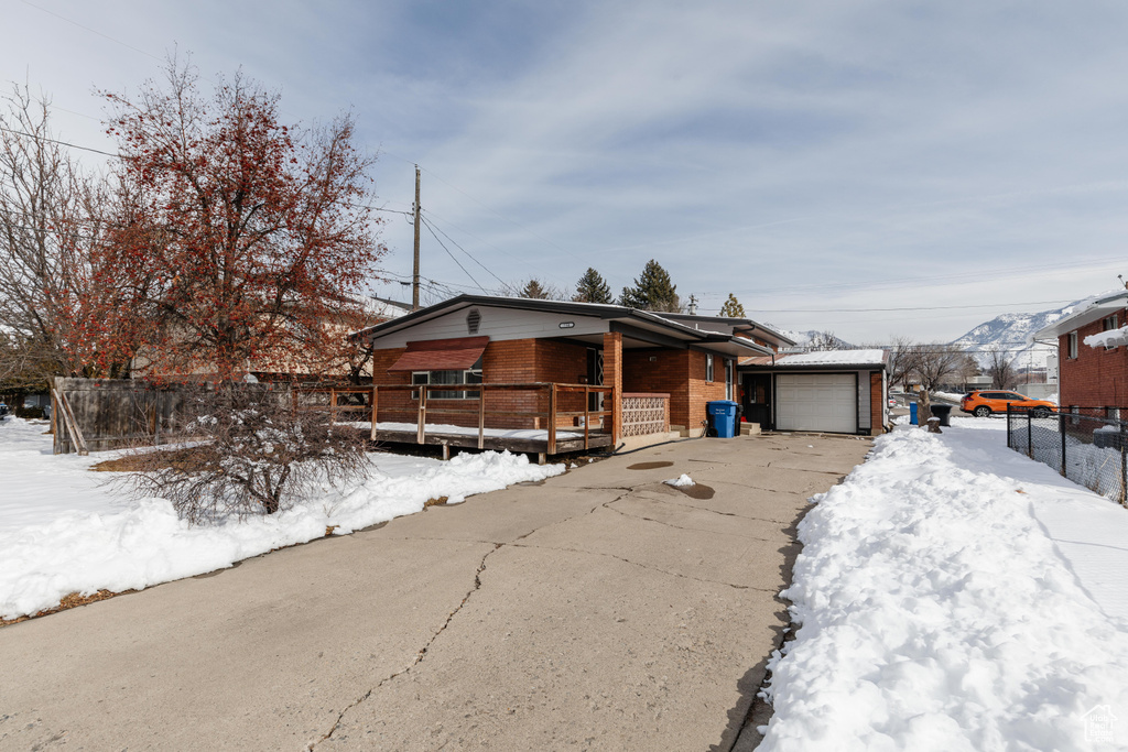 View of front of home with driveway, an outbuilding, an attached garage, fence, and brick siding