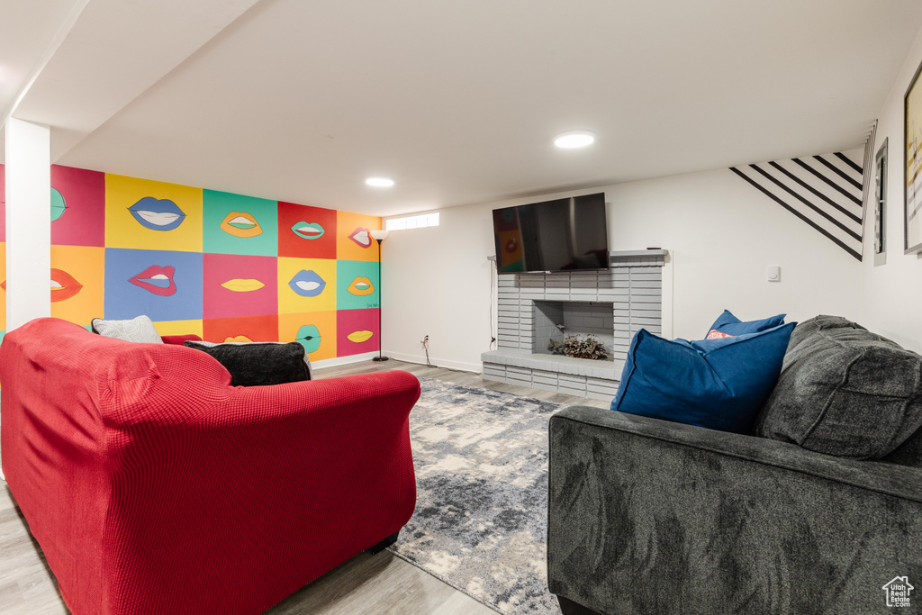 Living room with a fireplace, recessed lighting, light wood-style floors, an accent wall, and baseboards