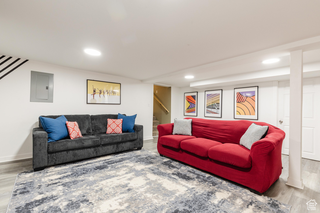 Living area with stairs, electric panel, wood finished floors, and recessed lighting