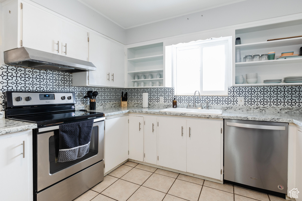 Kitchen with under cabinet range hood, stainless steel appliances, a sink, white cabinets, and open shelves