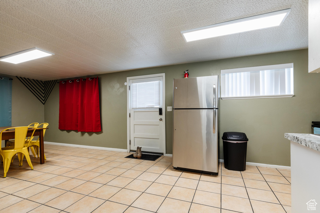 Kitchen with light tile patterned floors, baseboards, light countertops, and freestanding refrigerator