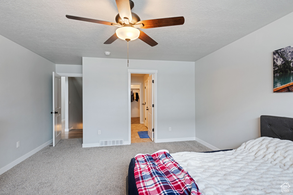 Bedroom with light colored carpet, visible vents, a textured ceiling, and baseboards