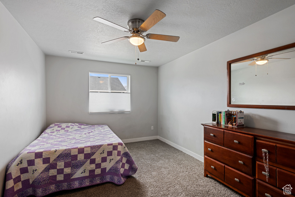 Bedroom featuring visible vents, light colored carpet, a ceiling fan, a textured ceiling, and baseboards
