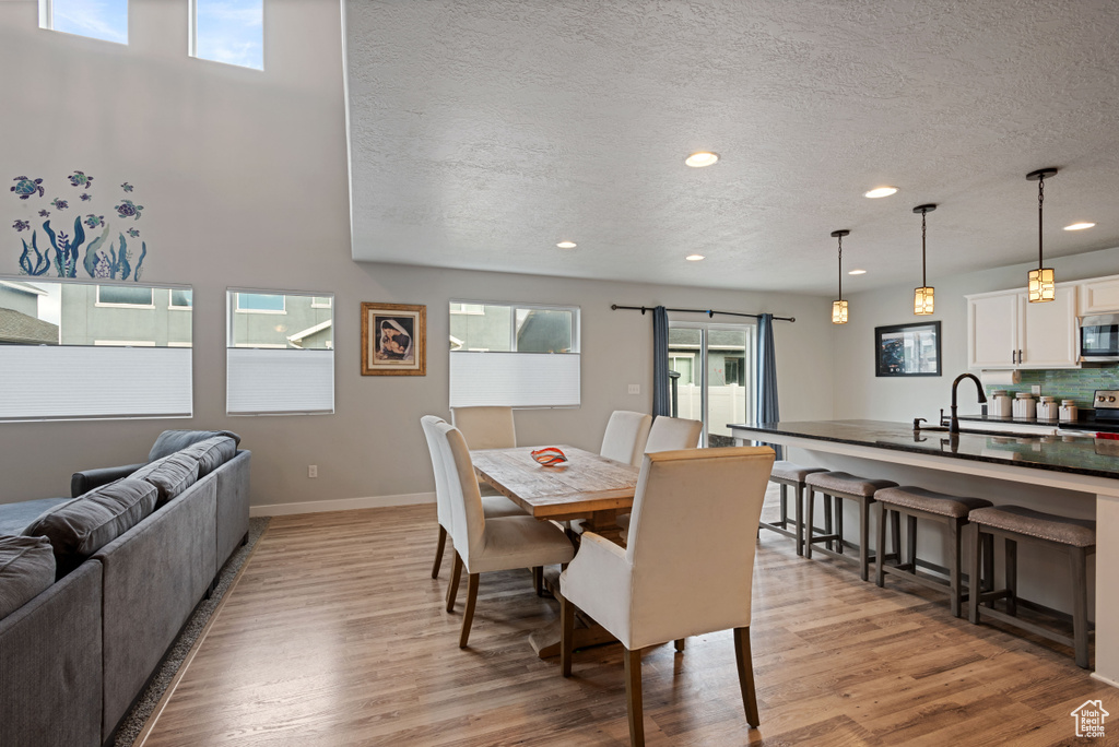Dining room featuring recessed lighting, light wood-style flooring, baseboards, and a textured ceiling