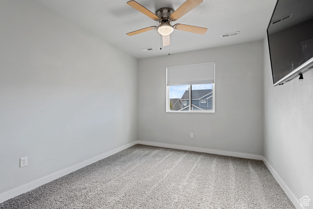 Carpeted spare room featuring a ceiling fan, visible vents, and baseboards