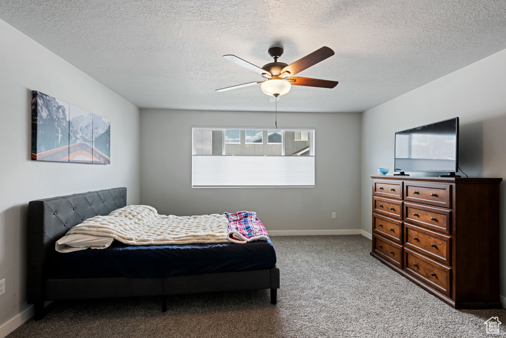 Bedroom featuring a ceiling fan, light colored carpet, a textured ceiling, and baseboards