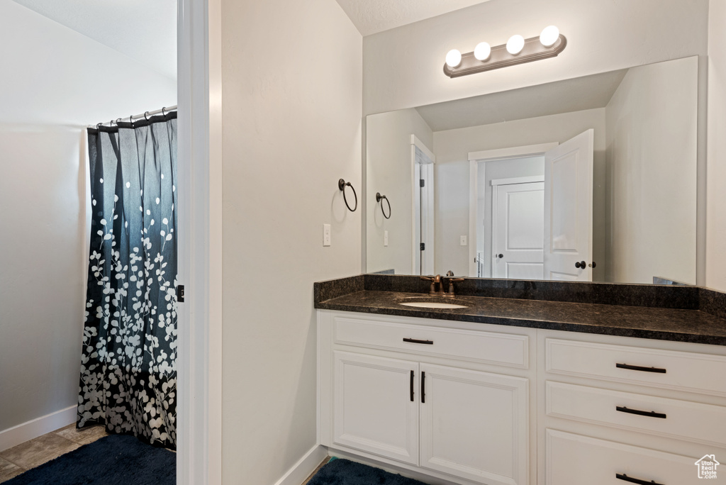 Full bath with tile patterned floors, baseboards, curtained shower, and vanity