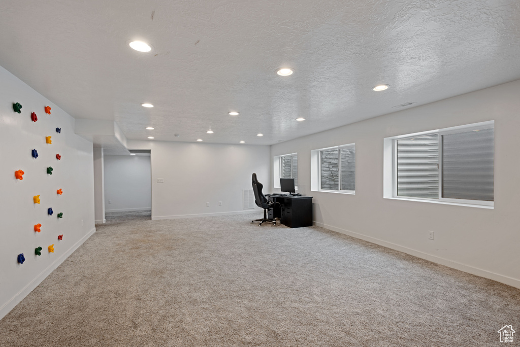 Unfurnished office featuring carpet floors, visible vents, baseboards, and a textured ceiling