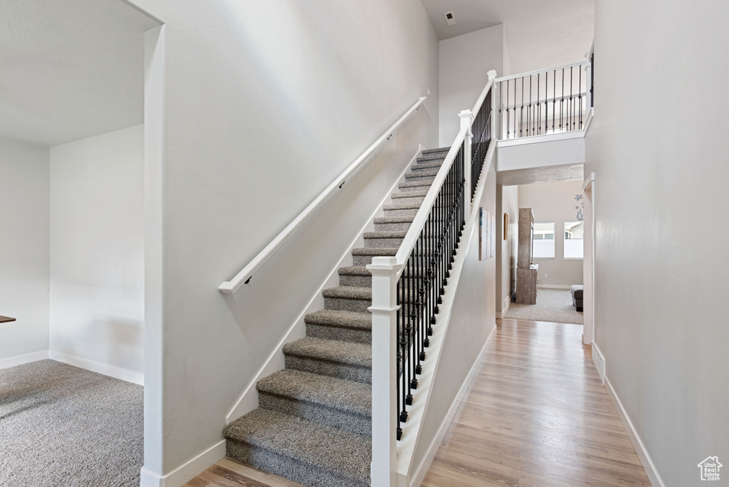 Stairs with a towering ceiling, baseboards, and wood finished floors