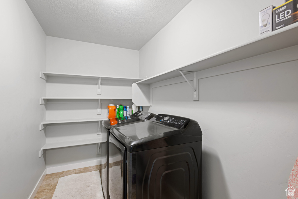 Laundry room featuring laundry area, a textured ceiling, baseboards, and washer and dryer