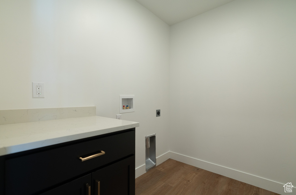 Laundry area with dark wood-style flooring, baseboards, hookup for a washing machine, cabinet space, and hookup for an electric dryer