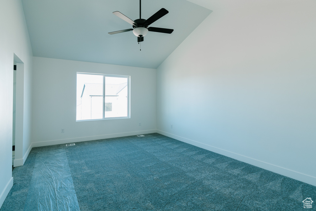 Carpeted empty room with baseboards, ceiling fan, and lofted ceiling
