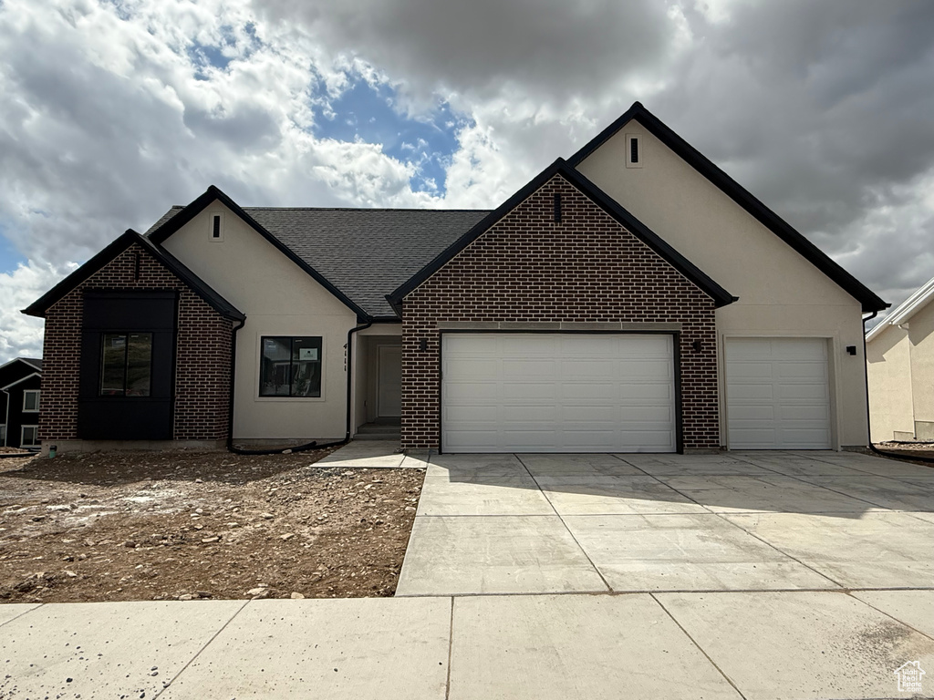 Single story home with an attached garage, driveway, stucco siding, and brick siding