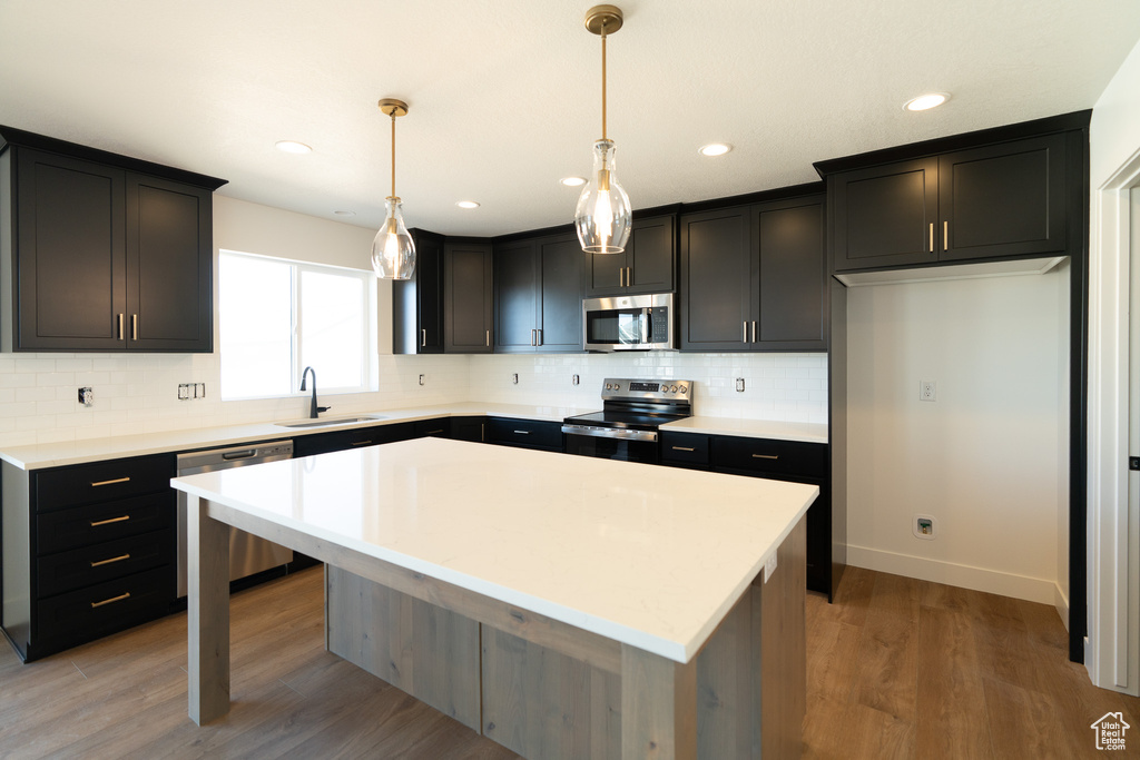 Kitchen featuring a sink, appliances with stainless steel finishes, a kitchen island, and tasteful backsplash