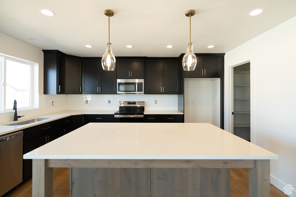 Kitchen with a sink, decorative backsplash, a kitchen island, and stainless steel appliances