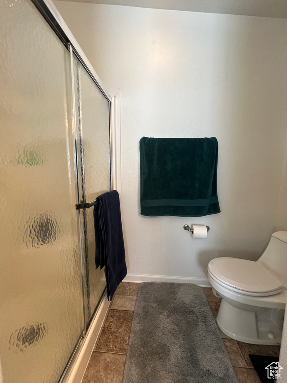 Bathroom featuring baseboards, a shower stall, and toilet