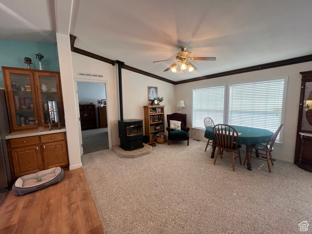 Dining area featuring visible vents, ornamental molding, a wood stove, vaulted ceiling, and ceiling fan