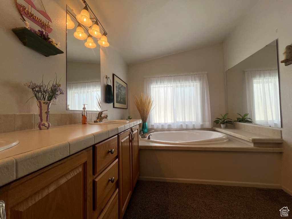 Bathroom featuring lofted ceiling, a healthy amount of sunlight, and a bath