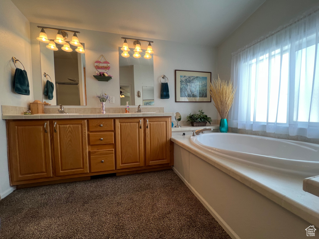 Full bathroom featuring a garden tub, double vanity, a sink, and lofted ceiling