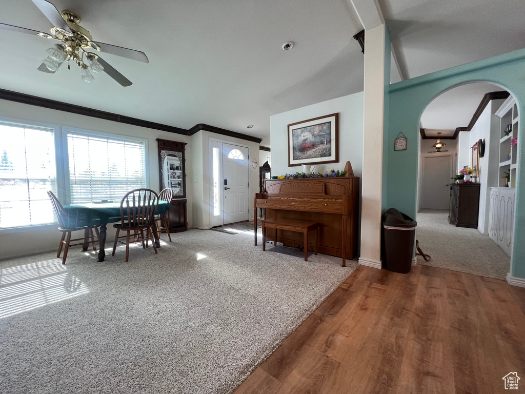 Dining space featuring arched walkways, a ceiling fan, and crown molding