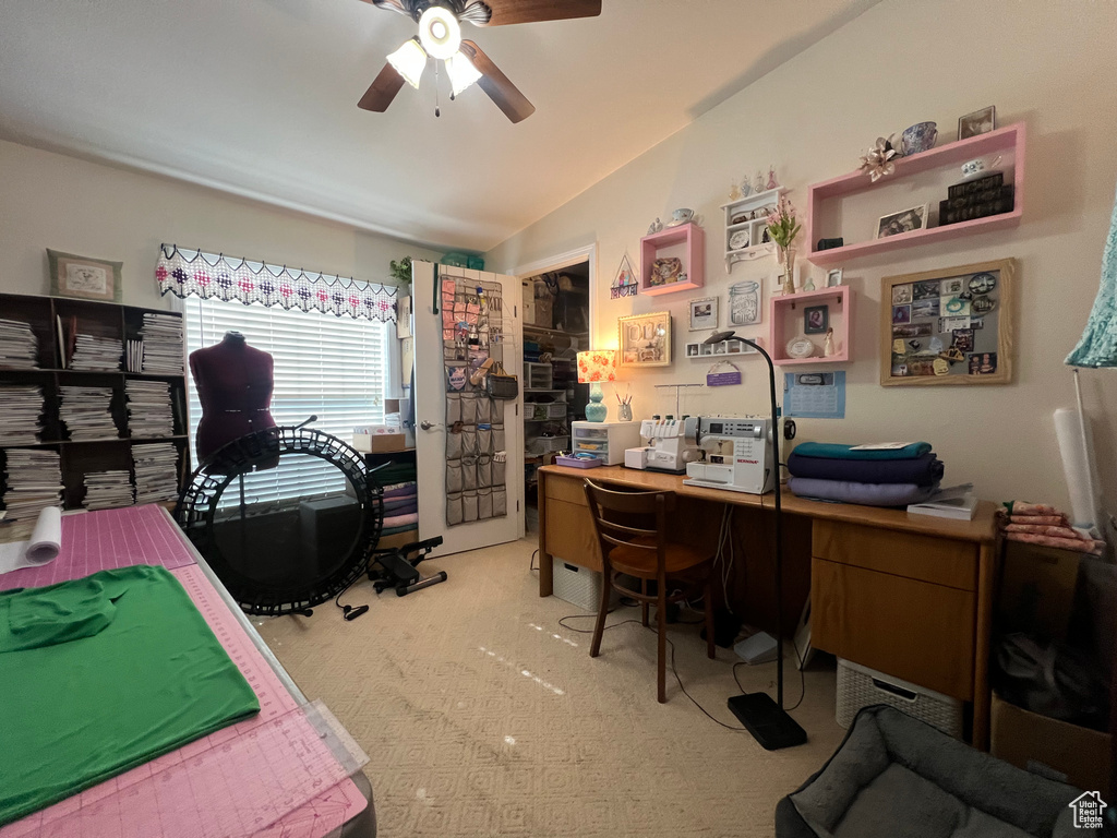 Home office featuring a ceiling fan, light colored carpet, and vaulted ceiling