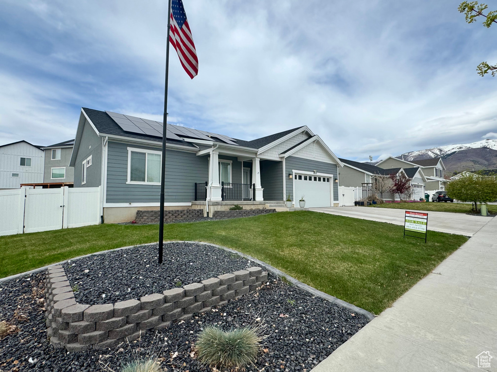 Ranch-style house featuring a gate, a porch, solar panels, and a front yard