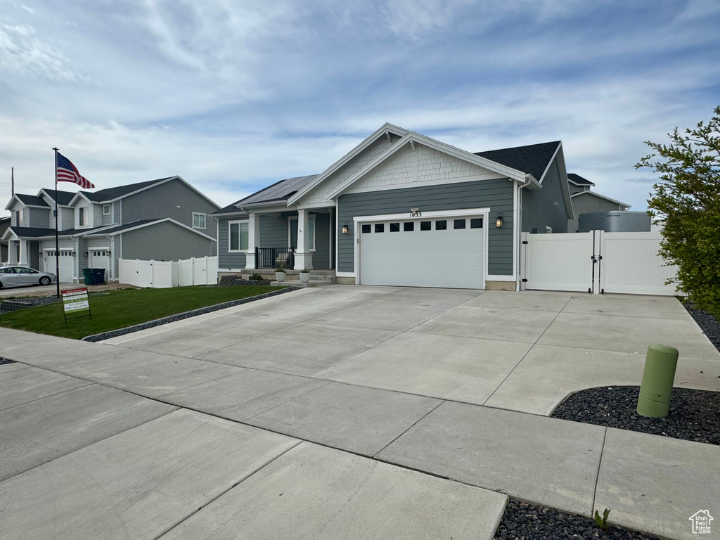 View of front of home featuring fence, a gate, concrete driveway, and a garage