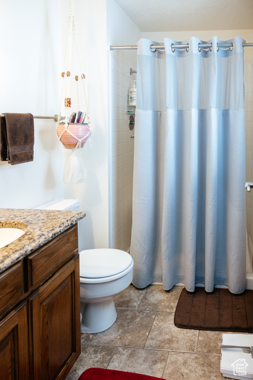 Bathroom featuring a tile shower, vanity, stone finish flooring, and toilet