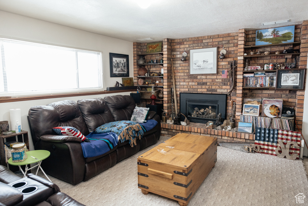Carpeted living area featuring a brick fireplace and a textured ceiling