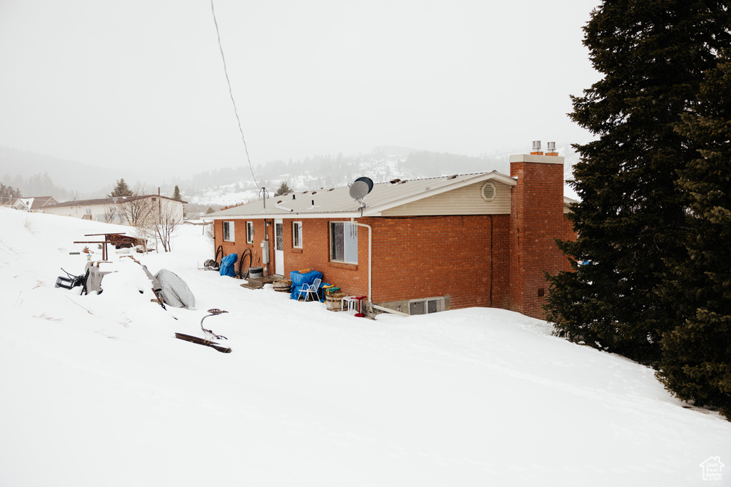 Snow covered house with a chimney and brick siding