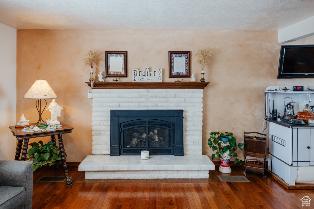 Living area with visible vents, baseboards, hardwood / wood-style floors, and a brick fireplace