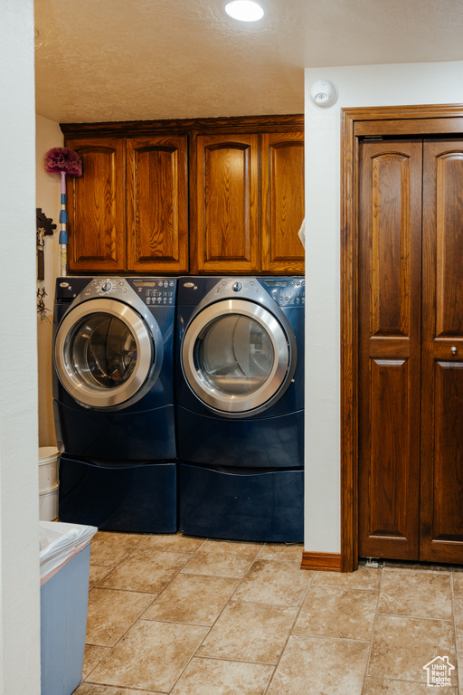 Clothes washing area featuring cabinet space, washer and clothes dryer, and baseboards
